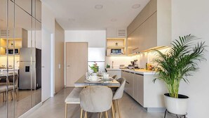 Una cocina moderna con comedor, que incluye una mesa con sillas, una planta en maceta y un refrigerador.