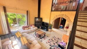 Ein Wohnzimmer mit einer Sofagarnitur, einem Fernseher, einem Kamin und einem Balkon.