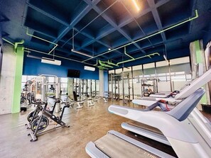 Ein Fitnessstudio mit Trainingsgeräten, einer Gewichtbank und einem Laufband.