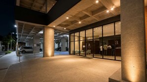 A modern building with a glass facade, a reception desk, and a parking area with cars. - Comfort Eden/Gym/Wi-fi/Parking/BBQ/ARENA (Monterrey)