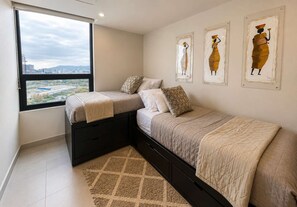 Un dormitorio con dos camas, un ventanal grande y tres obras de arte en la pared.