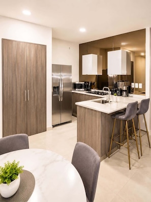 Una cocina moderna con una isla central, electrodomésticos de acero inoxidable y un área de comedor con una mesa redonda y sillas.