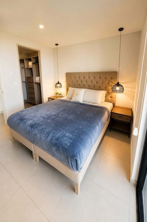 Ein Schlafzimmer mit einem großen Bett, einem Kleiderschrank, einem Nachttisch und einer Pendelleuchte.