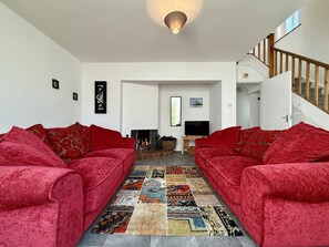 A living room with two red sofas, a patterned rug, a fireplace, and a TV. - Cottage 504 - Clifden - sleeps 5 guests  in 3 bedrooms (Clifden)