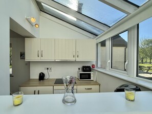 A modern kitchen with white cabinets, a microwave, a kettle, and a window with a view of the outdoors. - Cottage 504 - Clifden - sleeps 5 guests  in 3 bedrooms (Clifden)