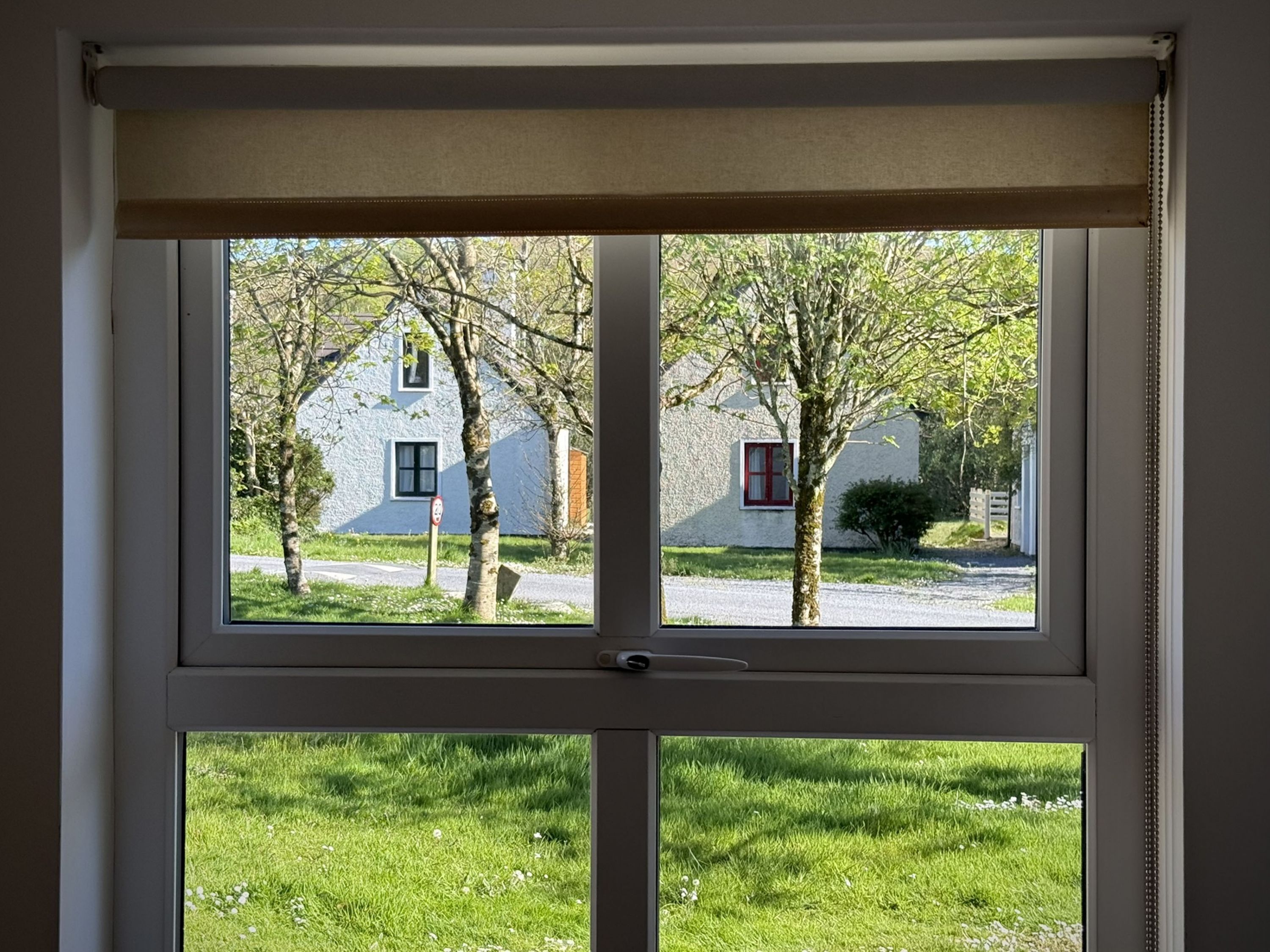 A window with a view of a house and trees.