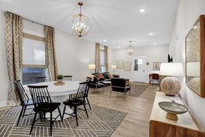 A modern living room with a dining area, featuring a round table, chairs, a sofa, and a coffee table.