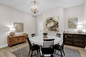 Comedor con una mesa redonda, sillas, una araña, obras de arte y un aparador.