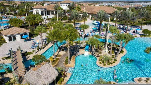 A resort with multiple swimming pools, palm trees, and a large building with a tiled roof. - Go!#34 - CHAMPIONS GATE (Davenport)