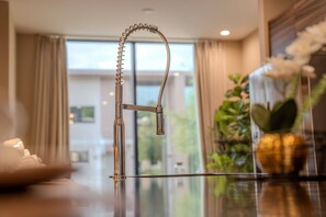 Ein modernes Badezimmer mit einem eleganten Wasserhahn, einer Duschkabine aus Glas und Blick ins Freie.