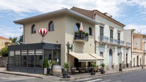 Un edificio con cafetería, mesas al aire libre y una decoración con globo aerostático.