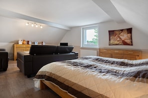 A bedroom with a bed, a desk, a chair, and a window.