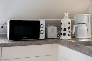 A kitchen with a microwave, toaster, coffee maker, and a decorative item on the counter.