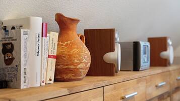 A wooden dresser with books, a ceramic vase, and electronic devices.