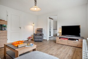 Una sala de estar moderna con un sofá, una mesa de centro, un televisor, una silla y una lámpara.