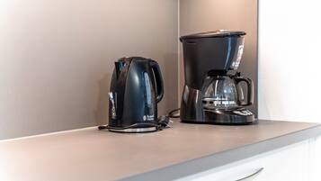 Eine Küchenarbeitsplatte mit einem schwarzen Wasserkocher und einer schwarzen Kaffeemaschine.