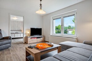 Ein modernes Wohnzimmer mit einer Couch, einem Couchtisch, einem Fernseher und einem Fenster mit Blick.