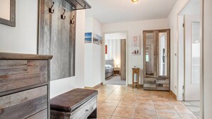 Un pasillo con un banco de madera, un espejo y una puerta que da a un dormitorio.
