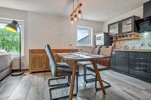 A modern kitchen with a dining table, chairs, a window, and built-in appliances.