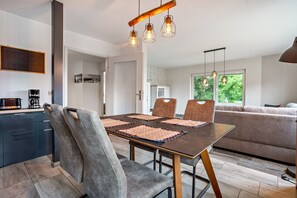 A modern kitchen with dark cabinets, a dining table with four chairs, and a large window with a view of greenery. - Apartment '3' with Wi-Fi (Gribow)