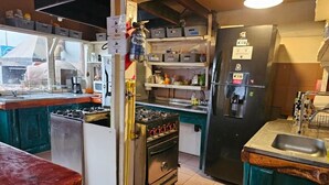 Une cuisine équipée d’une cuisinière à gaz, d’un four, d’un réfrigérateur et d’un évier.
