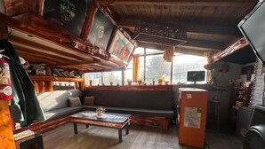 Ein gemütliches Zimmer mit Holzbalkendecke, einer Couch, einem Couchtisch und einem Fernseher.