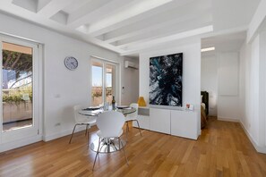 A modern kitchen with a dining area, wooden flooring, and a large abstract painting on the wall. - Suite House Cassia: Vacation Home with Mountain View, Wi-Fi, and Air Conditioning (Roma)
