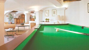 Ein Billardtisch in einem Raum mit hoher Decke und gewölbten Nischen.