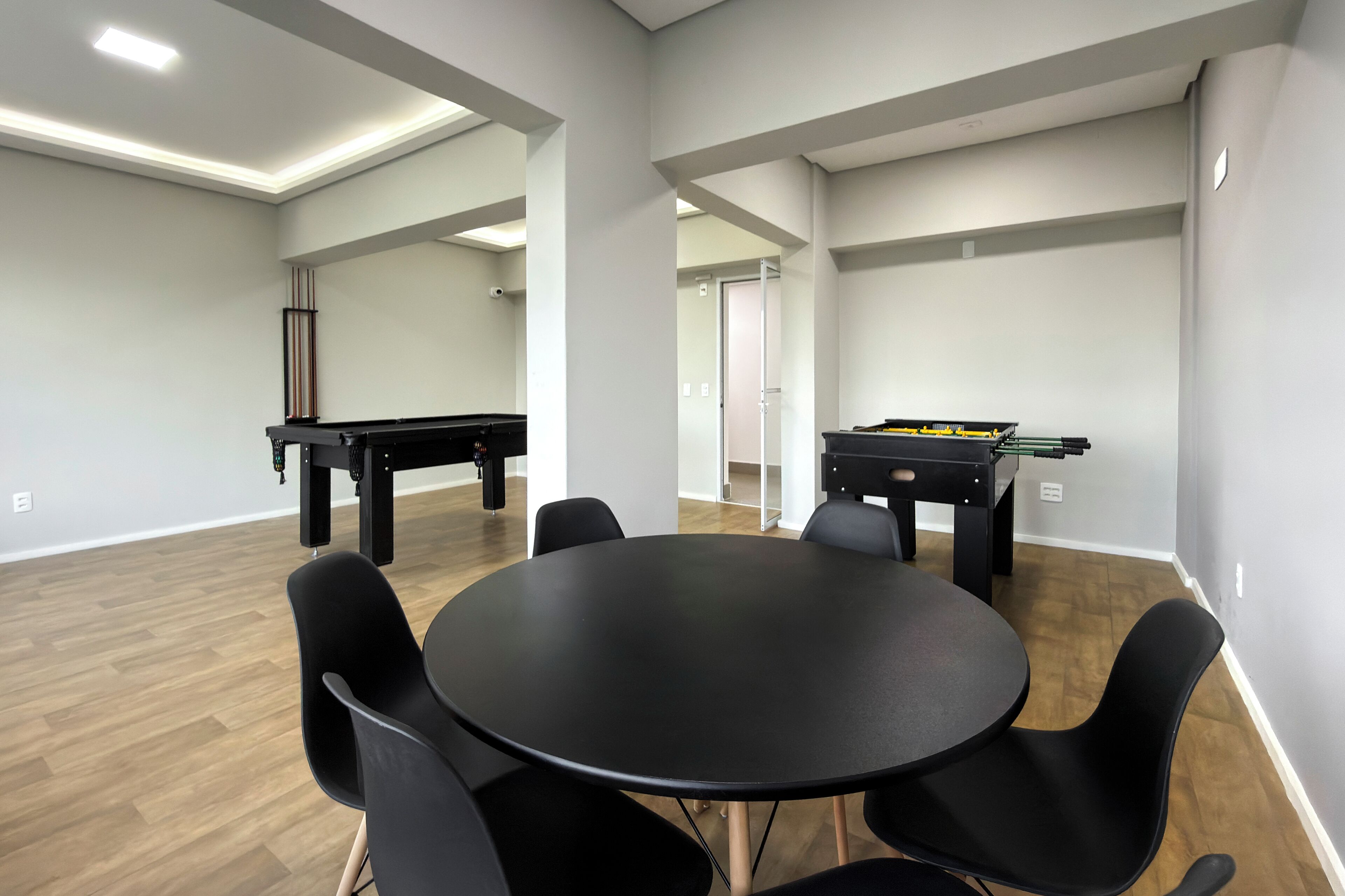 Une salle de conférence avec une table ronde, des chaises noires et deux tables de billard.