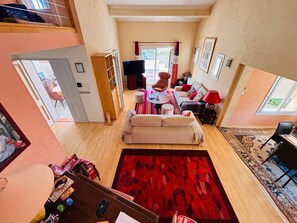 A spacious living area with a sofa, a television, and a dining table.