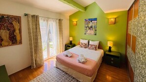 Quarto com cama, duas mesas de cabeceira, janela com cortinas e um quadro na parede.