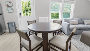A dining area with a round table and four chairs, a grey sofa, and a radiator.