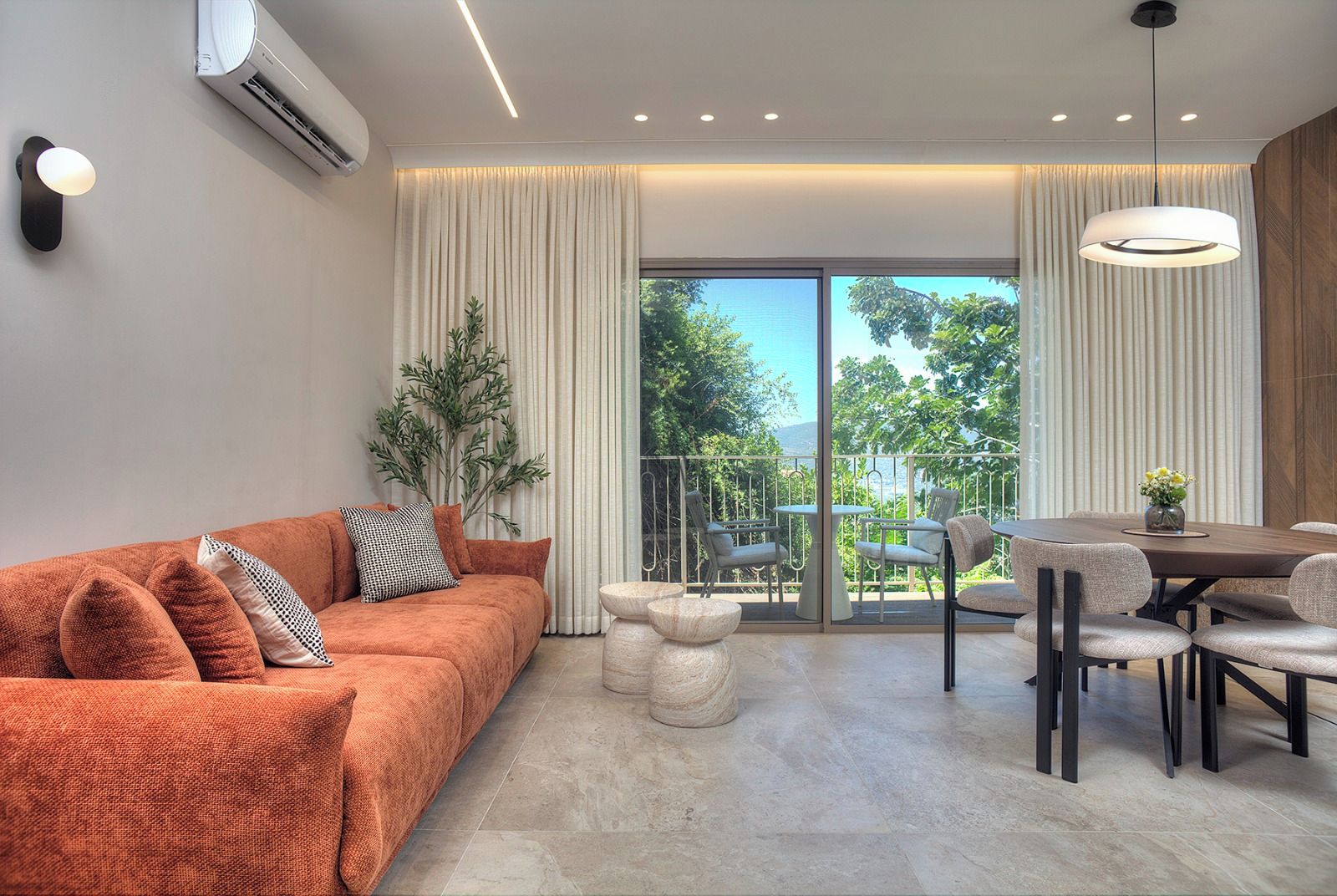Un salon moderne avec un canapé, une table à manger, des chaises et une vue sur l’extérieur.