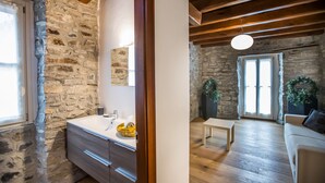 A stone-walled bathroom with a sink and a wooden ceiling.