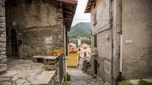 A narrow stone pathway leading to a building with a visible door and a small bench.