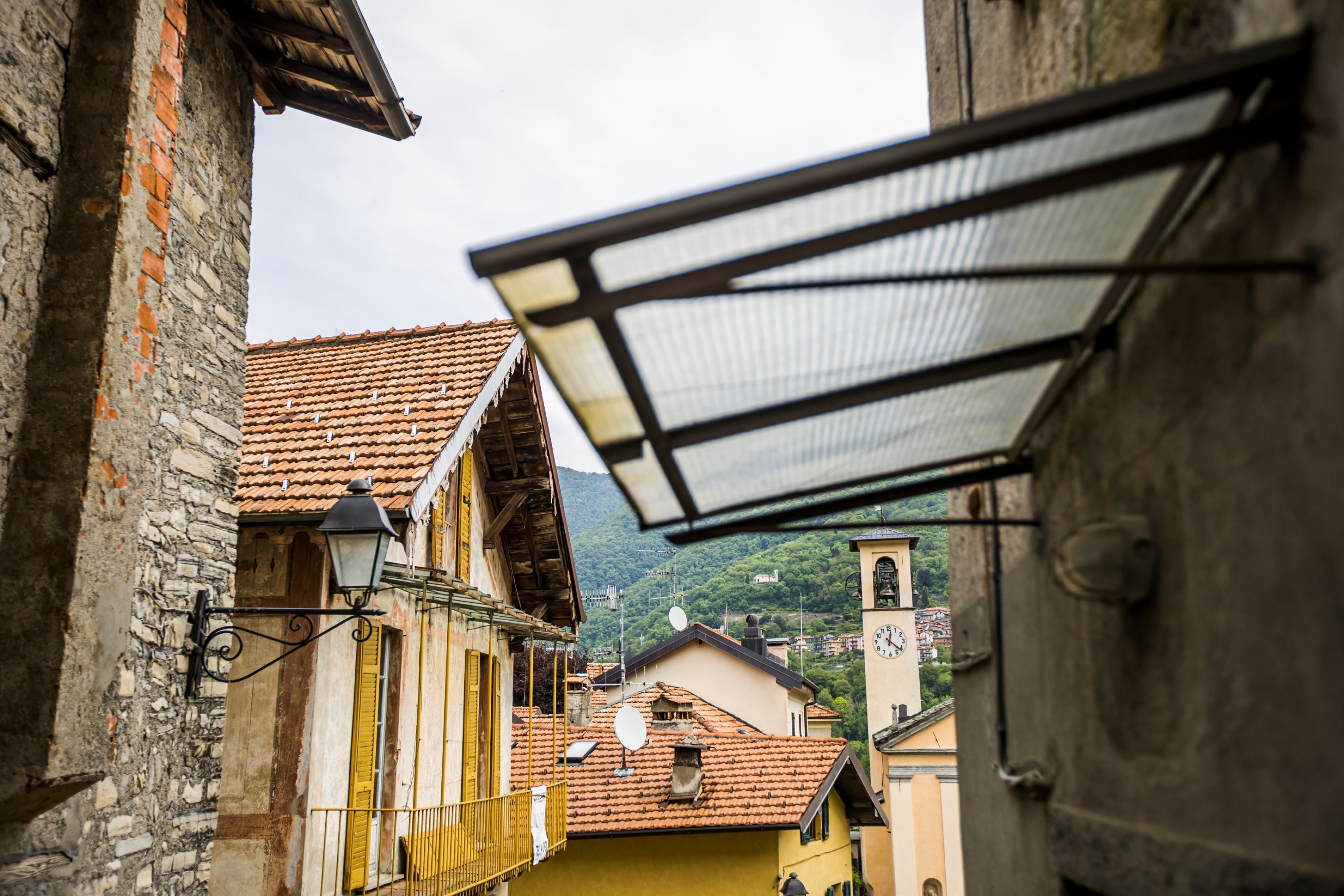 A narrow street with buildings, a bell tower, and a satellite dish.