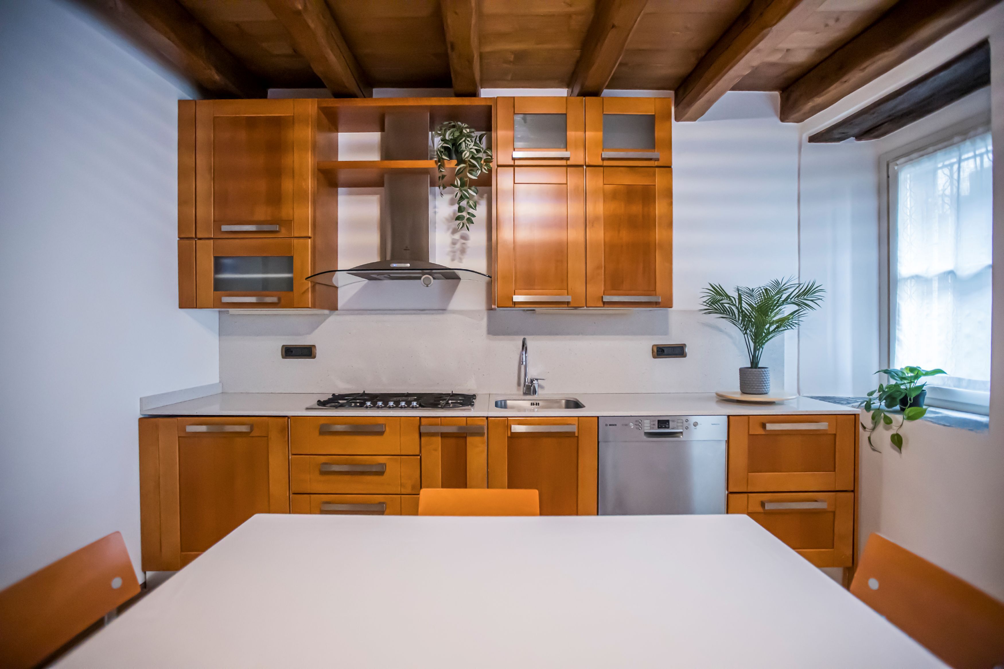 A modern kitchen with wooden cabinets, a white countertop, and a built-in dishwasher.
