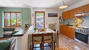 Une cuisine avec des meubles de rangement en bois, une cuisinière et une table à manger avec des chaises.