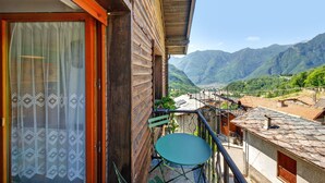 Un balcon en bois offrant une vue sur les montagnes, avec une table et une chaise.