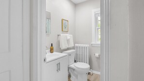 Een badkamer met toilet, wastafel, spiegel en radiator.