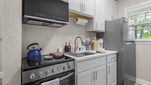 Une cuisine équipée d’une cuisinière, d’un évier et d’un réfrigérateur, avec des appareils en acier inoxydable et des meubles de cuisine blancs.