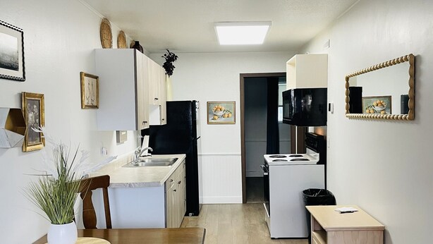 Eine moderne Küche mit weißen Schränken, einem Holztisch und einem schwarzen Kühlschrank.