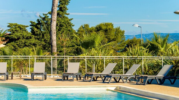 A swimming pool with lounge chairs and a metal railing, surrounded by greenery and trees. - Var Coast Duplex Apartment for 8 (Six-Fours-les-Plages)