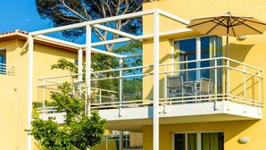 A yellow building with a balcony, a glass railing, and a tree in the background. - Var Coast Duplex Apartment for 8 (Six-Fours-les-Plages)