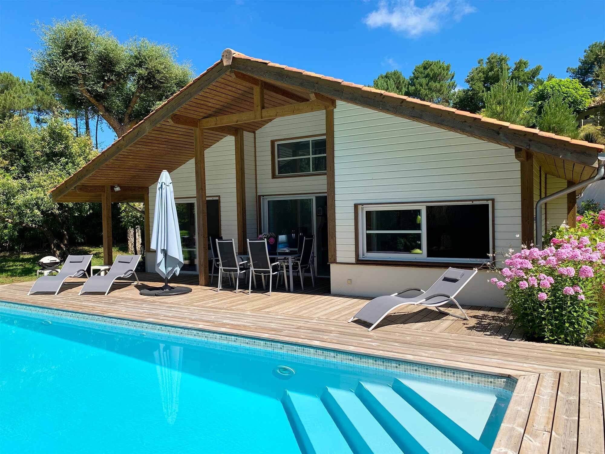 Un espace aménagé au bord de la piscine, avec des chaises longues, un patio couvert et une vue sur la piscine.