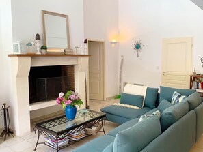 Ein Wohnzimmer mit Kamin, Sofa, Couchtisch und Bücherregal.
