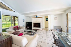 Ein Wohnzimmer mit Sofa, Fernseher, Kamin und Glastisch.