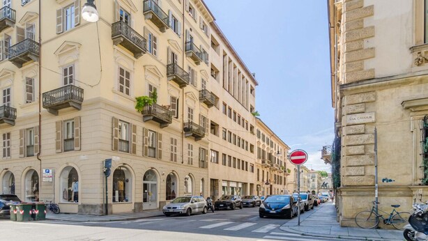 A street with parked cars, a no entry sign, and a building with balconies and arched windows. - GuestHost - Cozy Central Flat near Porta Nuova (Turin)