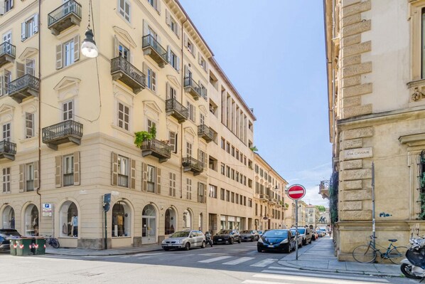 A street with parked cars, a no entry sign, and a building with balconies and arched windows. - GuestHost - Cozy Central Flat near Porta Nuova (Turin)