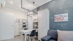 A compact living space with a dining table, a sofa, and a kitchenette. - GuestHost - Cozy Central Flat near Porta Nuova (Turin)